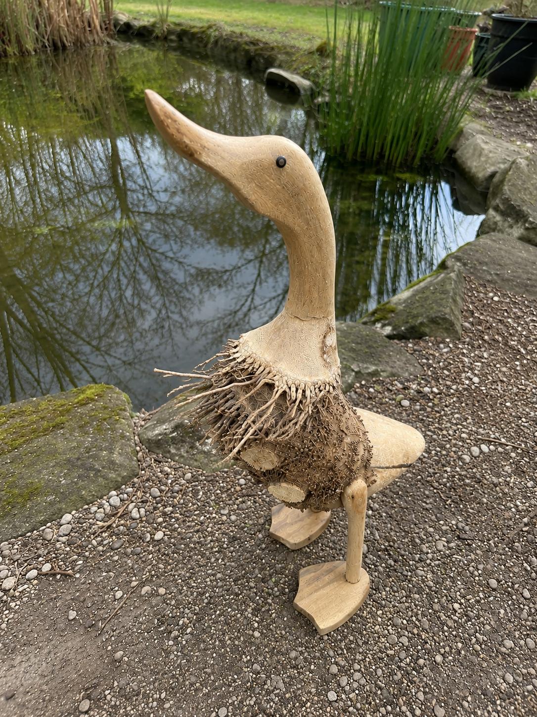 Canard en bois au bord d'un bassin ou d'une fontaine