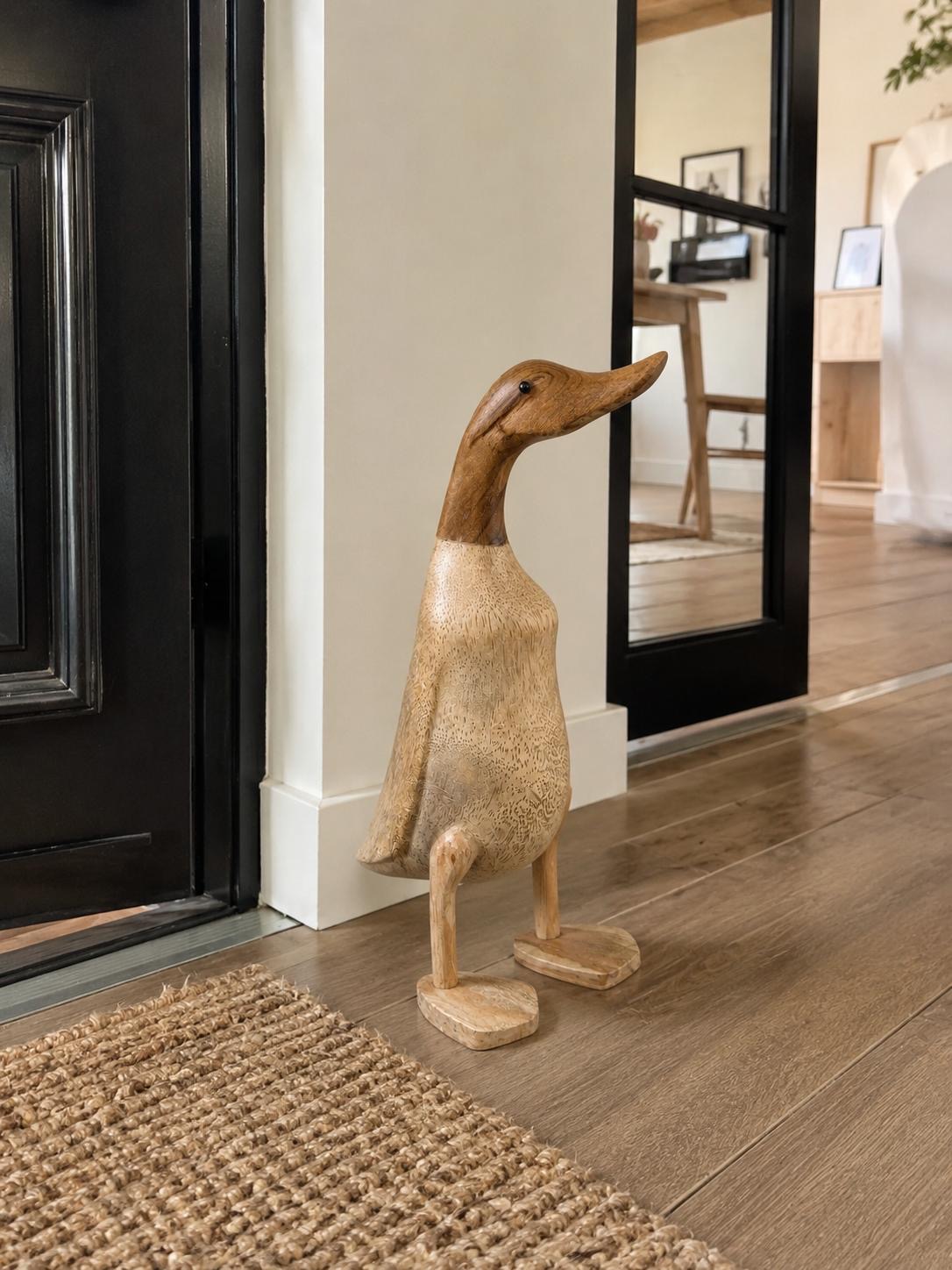 Canard en bois dans une entrée de maison, accueillant les visiteurs